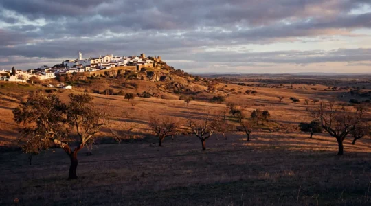 Village perché blanc de l'Alentejo sous lumière dorée d'hiver avec plaines infinies